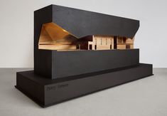 a model of a house on top of a black stand with gold foiled roof