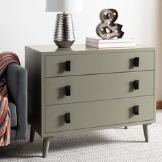 a grey chest of drawers sitting next to a lamp