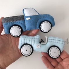 two handmade toy cars in the palm of someone's hand on a white background