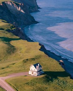 an aerial view of a white house on the side of a hill next to the ocean