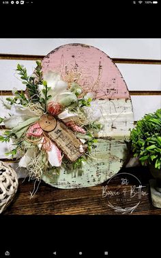 a wooden sign with flowers on it sitting next to a potted plant and other items