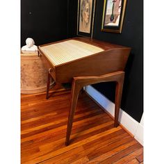 a wooden table sitting on top of a hard wood floor next to a painting and vase