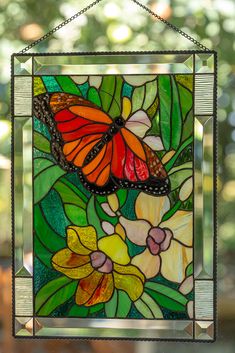 a stained glass window with a butterfly on it's wing and flowers in the background