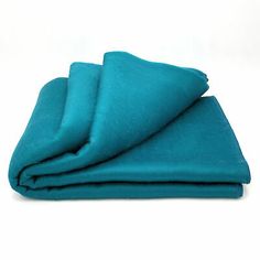 a teal colored blanket folded on top of each other in front of a white background