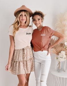 two women standing next to each other in front of a white wall wearing matching outfits