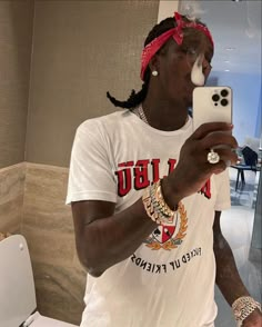 a man taking a selfie with his cell phone in front of him and wearing a red bandana