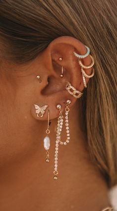 a close up of a person with ear piercings on their ears and wearing gold jewelry