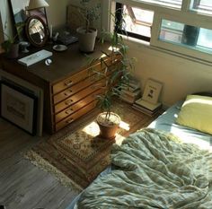 a bedroom with a bed, dresser and plant in the corner on top of it