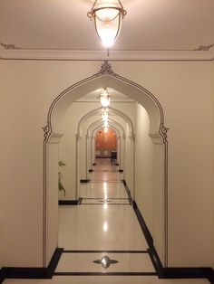 an empty hallway with white walls and black trim on the floor is lit by a light fixture