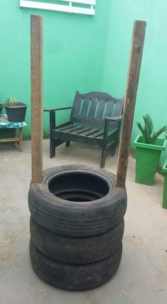 an old tire sitting on the ground next to a wooden bench and some potted plants