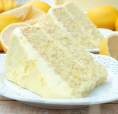 a slice of lemon velvet cake on a white plate with lemons in the background