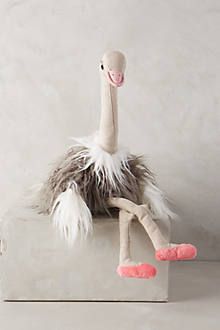 a stuffed ostrich sitting on top of a metal object with pink feet and legs