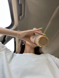 a woman is sitting in the back of a car drinking from a cup