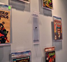 several comics are hanging on the wall with clear acrylic frames and magnets