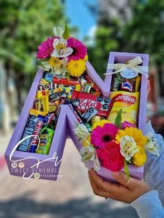 a person holding up a letter made out of candy and flowers