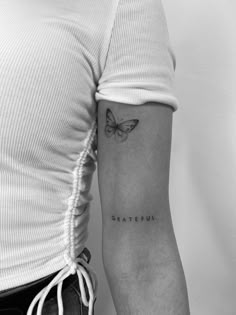 a black and white photo of a butterfly tattoo on the left upper arm, which reads grateful