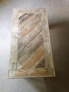 a table made out of pallet wood on top of a carpeted floor next to a wall