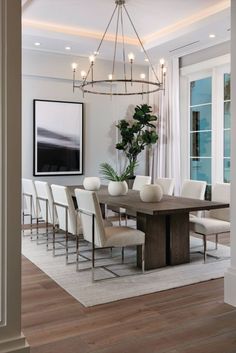 a dining room table with white chairs and a chandelier