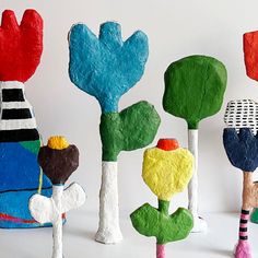 several colorful sculptures made out of clay and paper machs are displayed on a white surface