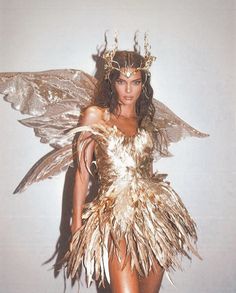 a woman in a gold costume with feathers on her head and wings around her body