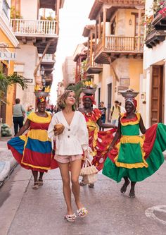 three women in colorful dresses are walking down the street