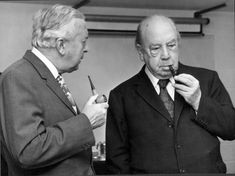 two men in suits and ties are looking at something on the other side of the man