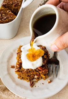 someone is pouring syrup over some food on a white plate with a fork and spoon