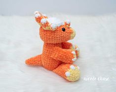 an orange crocheted stuffed animal sitting on top of a white fur covered floor