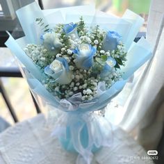 a bouquet of white and blue flowers sitting on top of a table