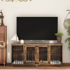 a flat screen tv sitting on top of a wooden cabinet next to a clock and plant