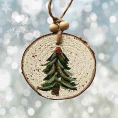 a wooden ornament with a christmas tree on it hanging from a string and snowflakes in the background