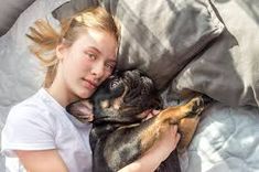 a woman laying in bed with her dog