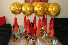 gold balloons with red tassels are hanging from the ceiling in front of a black couch