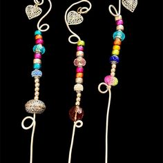 three necklaces with different colored beads and hearts hanging from the strings on a black background