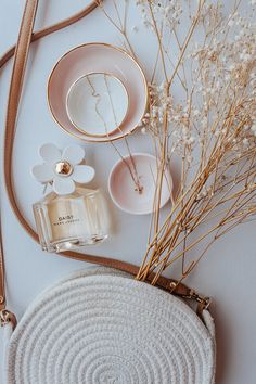 a white purse sitting on top of a table next to a flower vase and plate