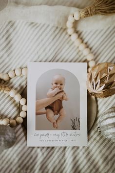 a card with an image of a baby on it sitting on a bed next to beads