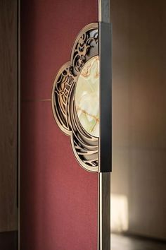 a clock on the side of a red wall next to a door with an intricate design