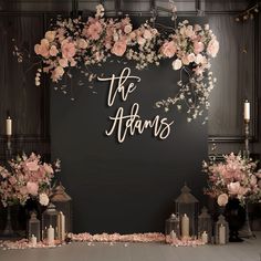 a black wall with pink flowers and candles