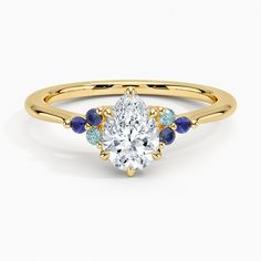 a yellow gold ring with an oval cut diamond surrounded by blue sapphires and diamonds