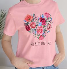 My Kids Love Me Jersey Short Sleeve Tee, Beautiful floral heart shirt for mom , Gift for mom, Mother's Day shirt, Flower tshirt for moms This classic unisex jersey short sleeve tee fits like a well-loved favorite. Soft cotton and quality print. These t-shirts have-ribbed knit collars to bolster shaping. The shoulders are tapered for a better fit over time. Dual side seams hold the garment's shape for longer.  .: Made with 100% Airlume combed and ring-spun cotton, a lightweight fabric (4.2 oz/yd² (142 g/m that is easy to layer, breathable. Perfect for active and leisure wear.  .: The retail fit that is perfect for casual and semi-formal settings. The crew neckline adds a classic, neat style that's perfect for accessorizing. .: Bella+Canvas manufactures all its products in the US and interna Pink Tops For Mother's Day Gift, Printed Pink T-shirt As Gift, Pink Top For Mother's Day Gift, Floral Print Cotton Tops For Mother's Day, Cotton Top With Floral Print For Mother's Day, Cotton Tops With Heart Print For Mother's Day, Pink Printed T-shirt As A Gift, Floral Print Short Sleeve Top For Mother's Day, Floral Print Short Sleeve Top