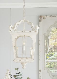 a white lantern hanging from the ceiling in a room with flowers and other decorations on it