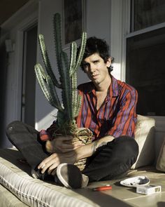 a man sitting on a couch holding a potted plant