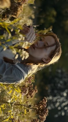 a woman standing next to a tree with leaves