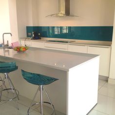 two blue stools sit at the center of a kitchen island with white countertops