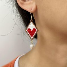 These Red Heart Drop Earrings are the perfect birthday gift for a sister who appreciates unique handmade jewelry. Adorned with lustrous freshwater pearls and a diamond shape with small red heart.these exquisite handwoven earrings are sure to make a statement. The intricate brick stitch design adds a touch of elegance to these one-of-a-kind earrings. Treat your sister to a truly special and thoughtful gift with these beautiful Heart Drop Earrings. Closure: hook Length: 2.56 inches Width: 0.8 inches Quantity:1 pair Handmade Heart Earrings For Valentine's Day Gift, Heart Beads Drop Earrings For Gift, Handmade Dangle Heart Earrings For Gift, White Beaded Earrings With Heart Beads As A Gift, White Heart Earrings With Ear Wire As A Gift, Handmade Beaded Drop Earrings For Gifts, Handmade Red Earrings For Mother's Day, White Hypoallergenic Beaded Earrings As Gift, Hypoallergenic White Beaded Earrings Gift