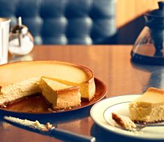 a piece of cheesecake on a plate next to a knife and fork, with one slice missing