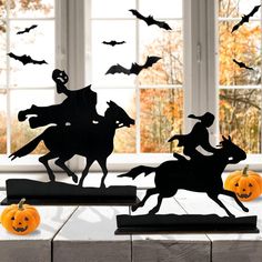 halloween scene with pumpkins and horse silhouettes on table in front of window,