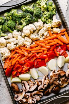 an assortment of vegetables are laid out in a tray on the table, including broccoli, cauliflower, carrots and mushrooms