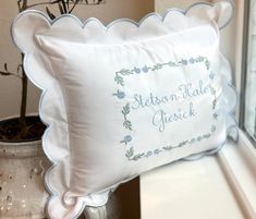 a white pillow sitting on top of a window sill next to a potted plant