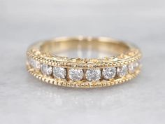 a gold wedding band with five diamonds on top and two rows of white stones in the middle